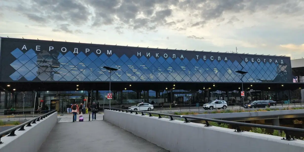 Belgrade Nikola Tesla Airport terminal showing different transportation options including buses, taxis and private transfer vehicles